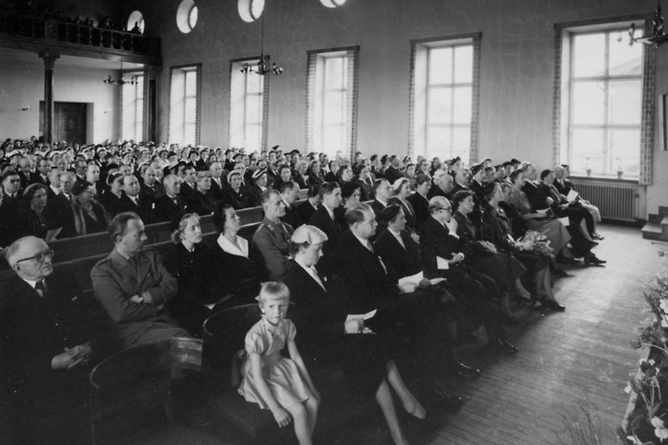 Invigning av Husliga seminariet i maj 1955. Bland gästerna fanns statsminister Tage Erlander och hertiginnan av Västerbotten, prinsessan Sibylla. Högtidstalen hölls hos grannen Folkskoleseminariet, med stor aula. Trots olika stilar, storlek och tillkomsttider (Folkskoleseminariet byggdes 1923–1924) finns viss samhörighet mellan de två skolkomplexen – något som arkitekten Nils Tesch verkar ha strävat efter. Gösta Skoglunds arkiv, Folkrörelsearkivet i Västerbotten.