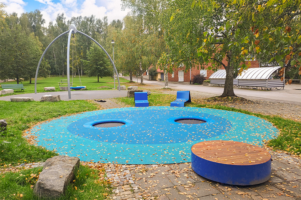 Elevlunden i höstskrud med studsmattor och sittbänkar i förgrunden och en gungställning i bakgrunden.