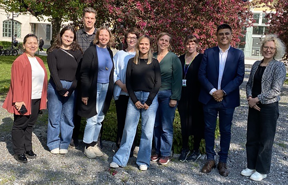 Gruppbild av tio personer utomhus i solen.