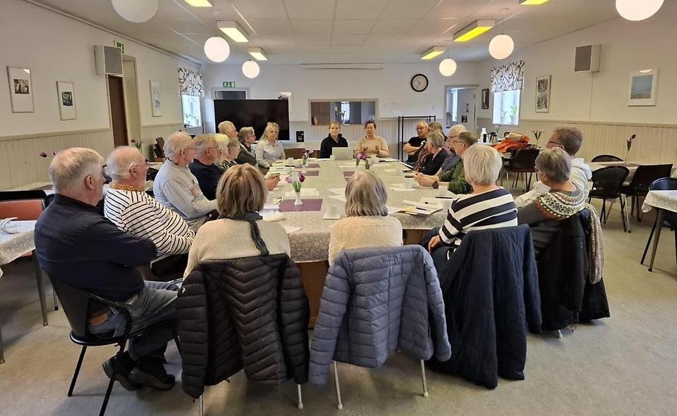 Stor lokal med många människor som sitter runt ett bord. 