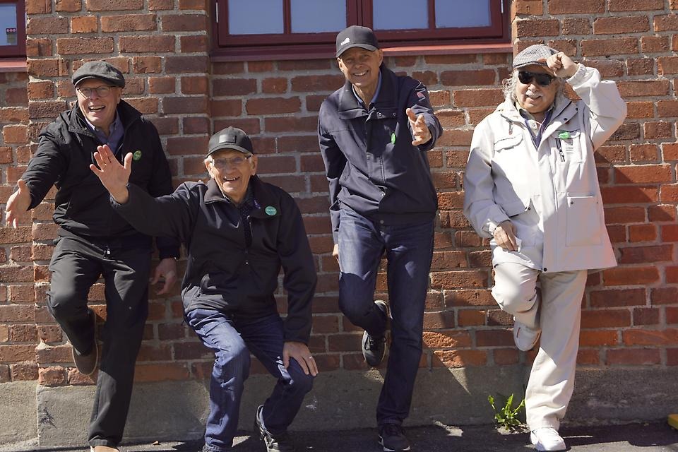 Fyra män som står mot en stenvägg