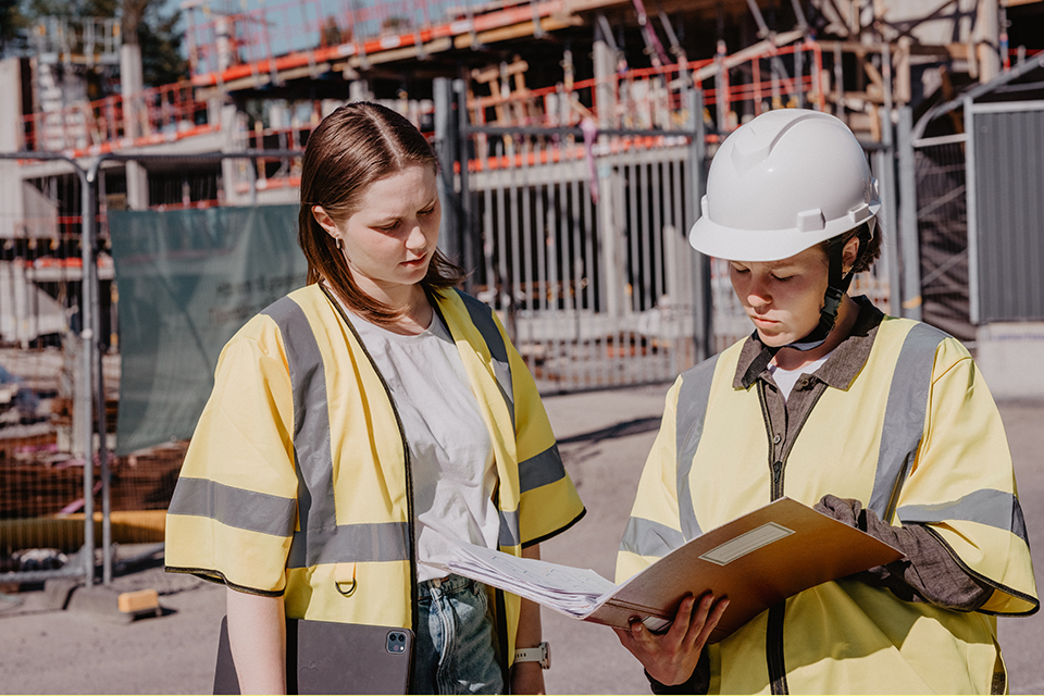 Två kvinnliga byggarbetare samtalar.