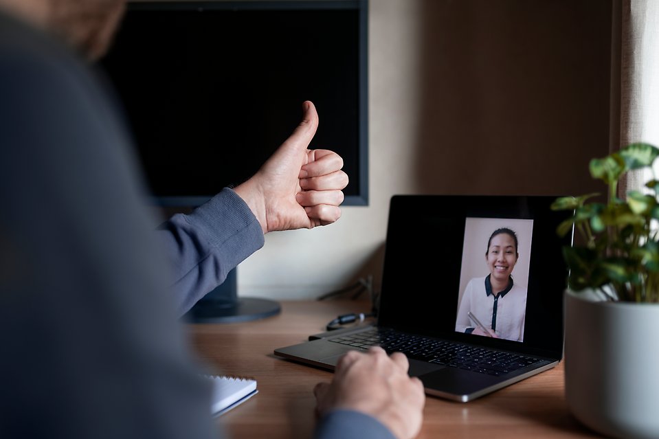 En person som ger tummen upp till en laptop